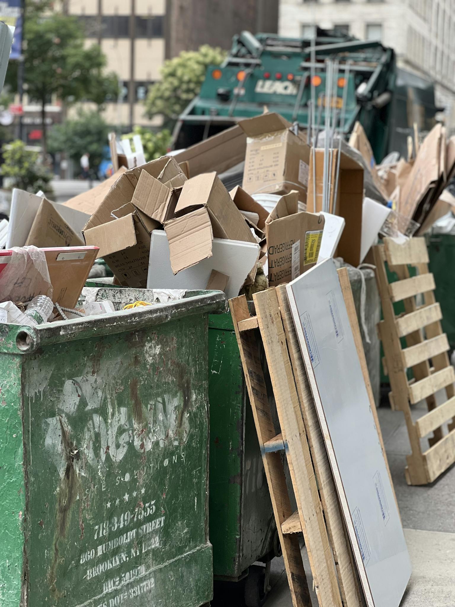 Piled cardboard boxes and waste in a city dumpster highlight urban recycling.